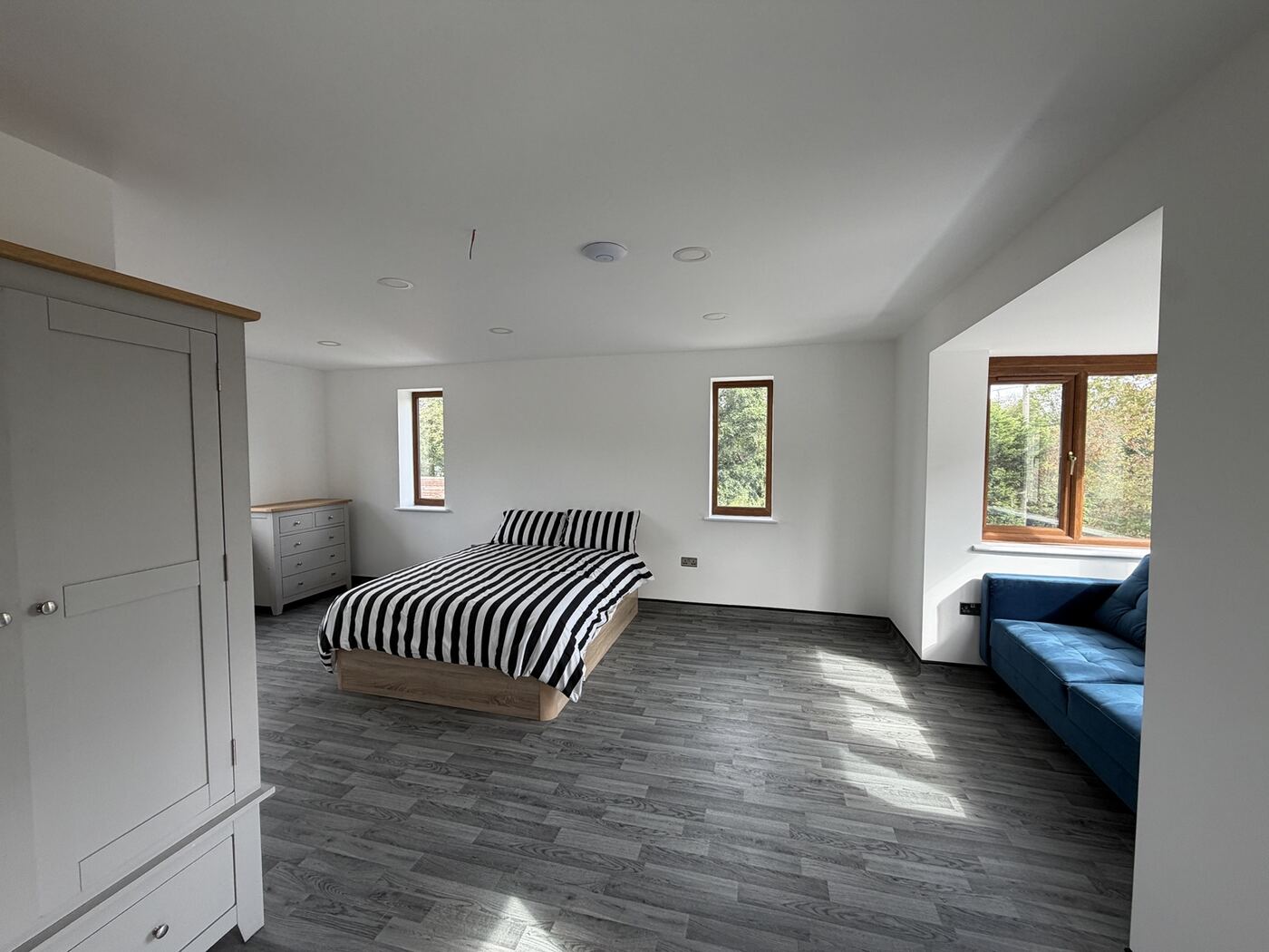 Bedroom with wood-effect safety flooring and oak windows