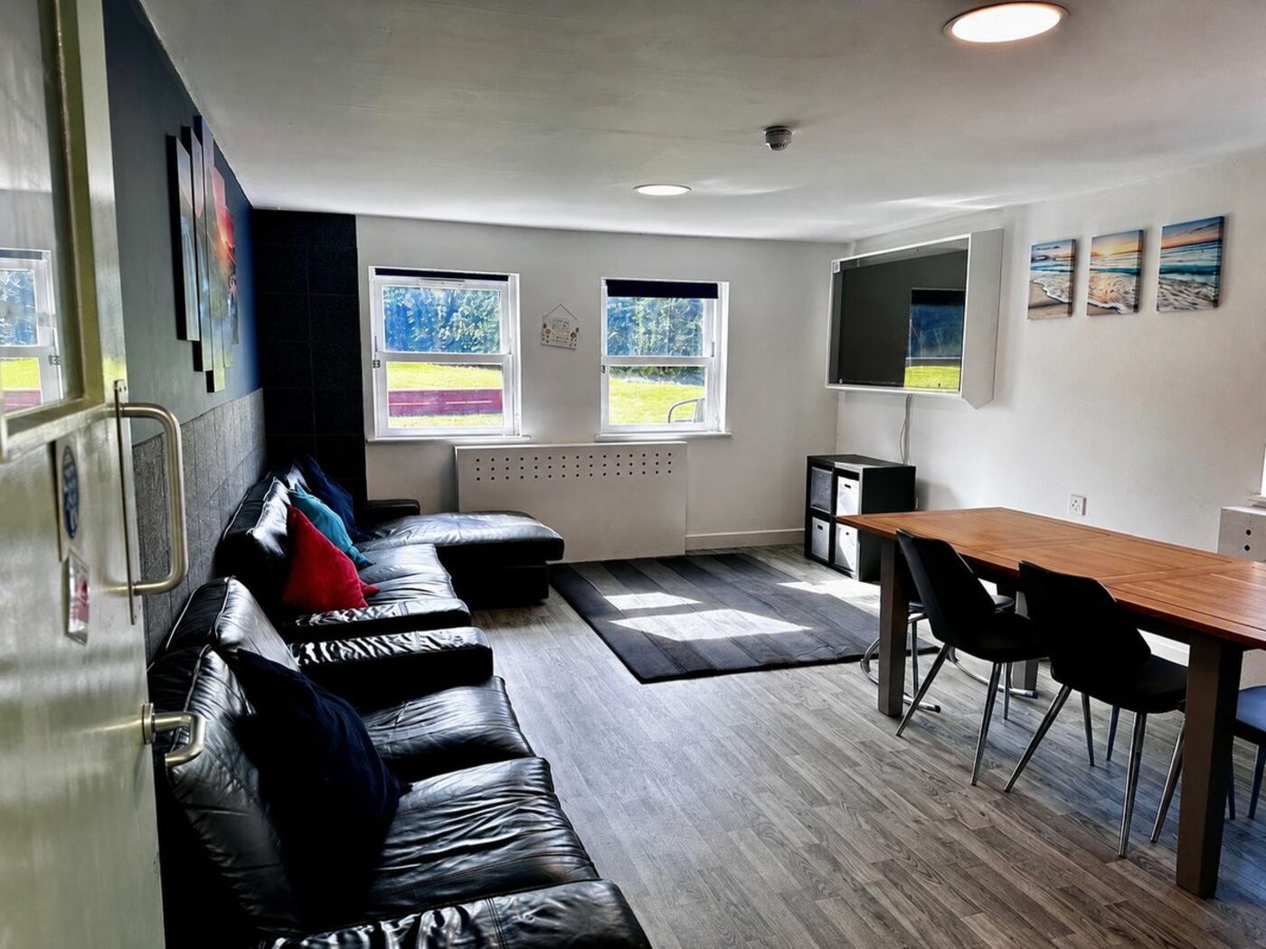 Shared lounge with leather sofas, wall-mounted television and dining table